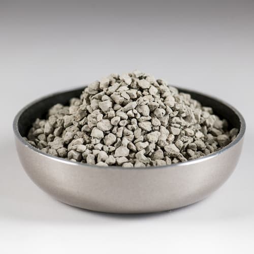 Bowl of coarse grey bentonite granules used in industrial absorbent applications